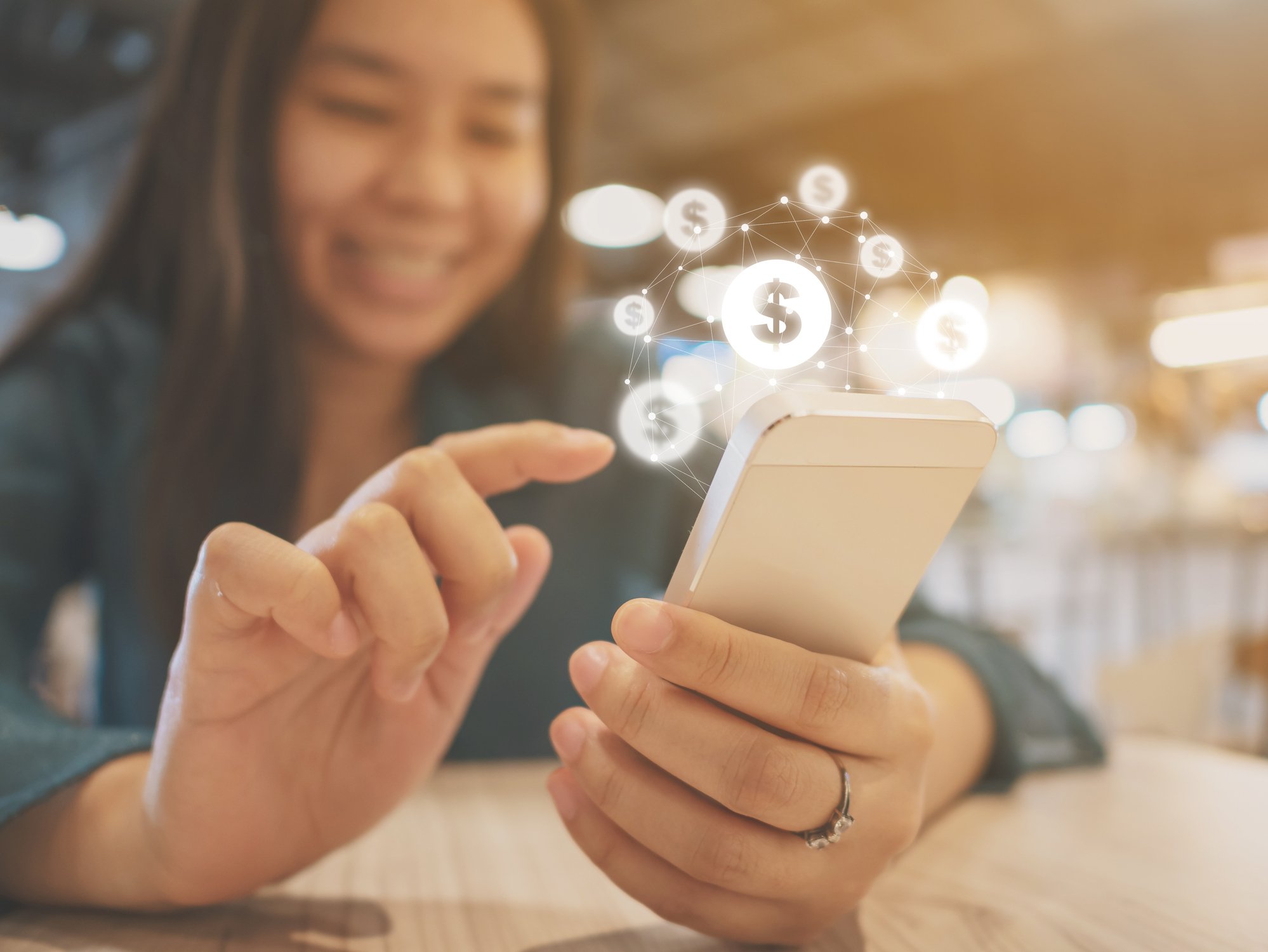 GIrl tapping on smartphone with currency symbols floating around in the air