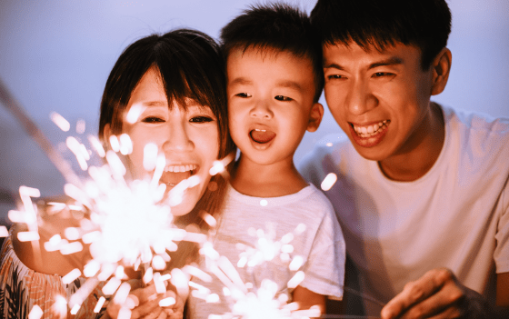 Man, woman and child looking at sparklers